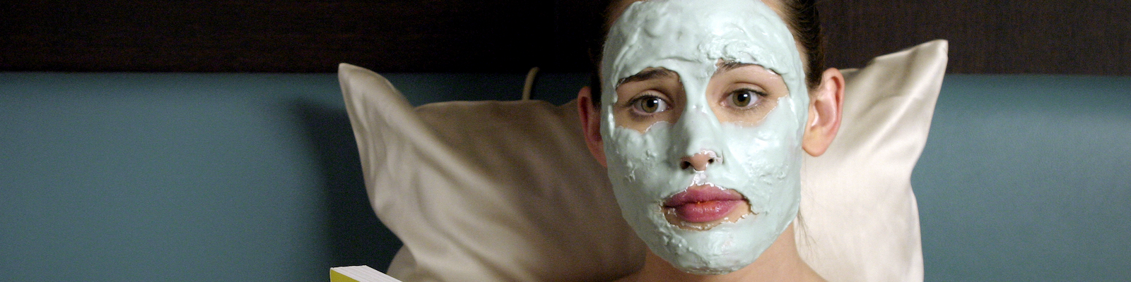 Jennifer Garner sits in bed with a green lotion on her face reading 