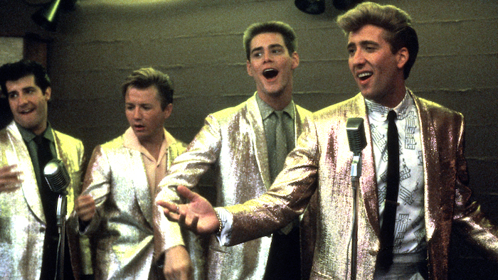 Nicolas Cage and Jim Carrey perform with doo wop vocal group dressed in matching metalic gold jackets in Peggy Sue Got Married