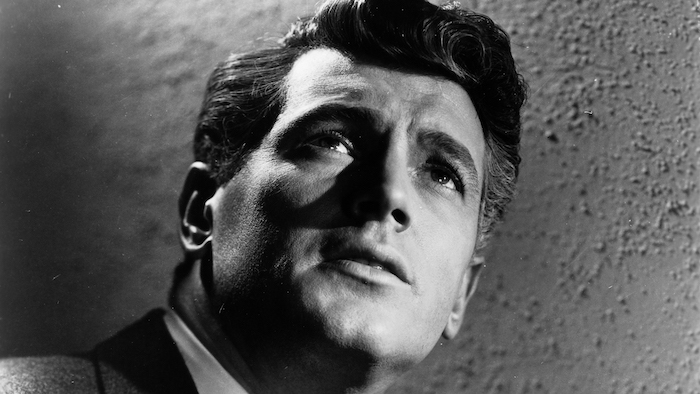 A dramatically lit Rock Hudson appears in close-up in a publicity photo for Magnificent Obession