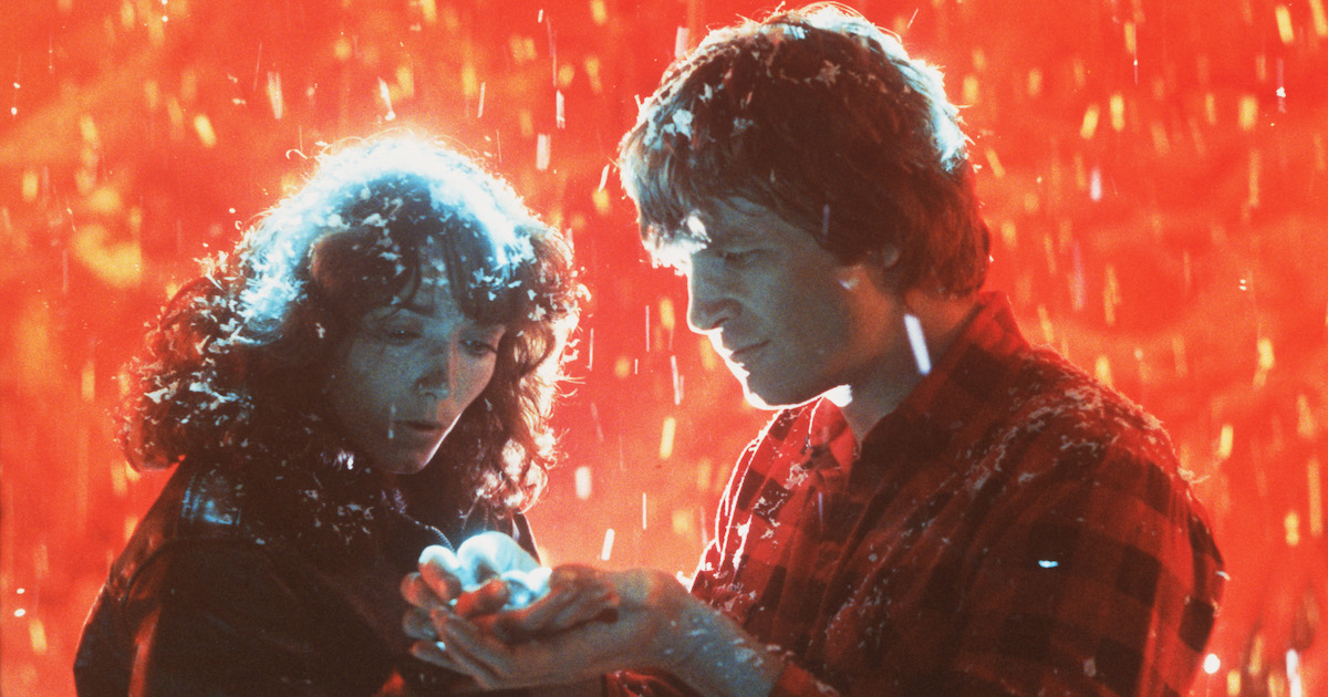 Nancy Allen and Jeff Bridges look at a glowing light they hold in their hands in Starman