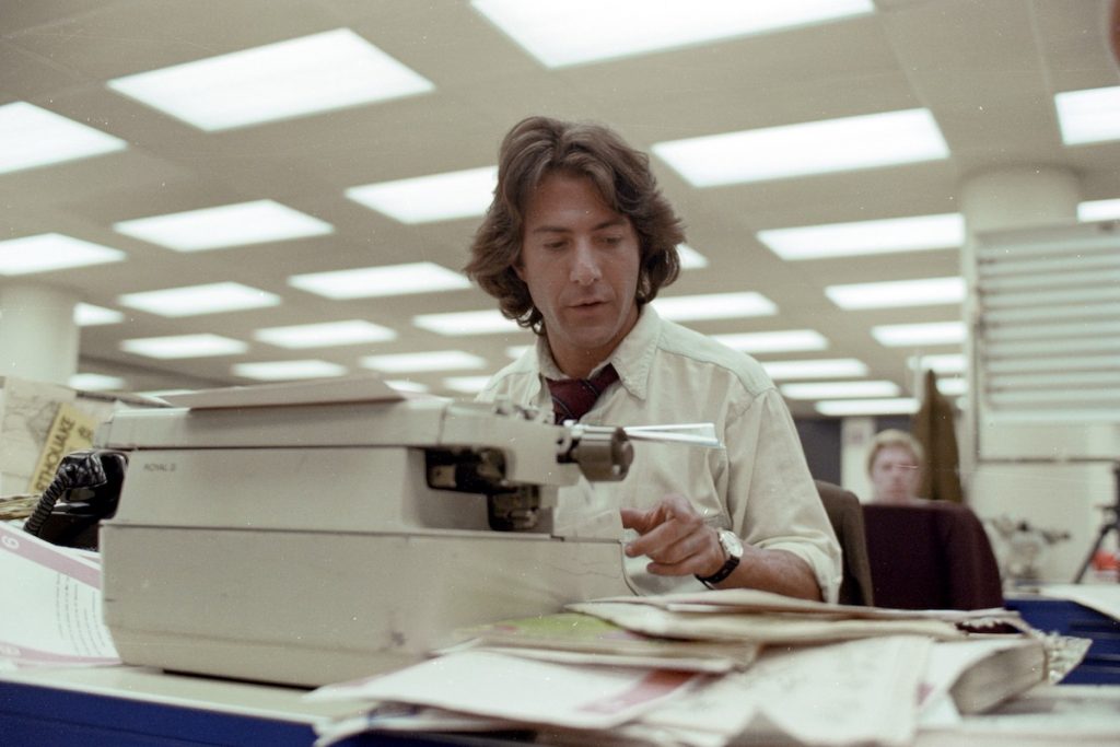 Dustin Hoffman as Carl Bernstein sits at a typewriter in All the President's Men