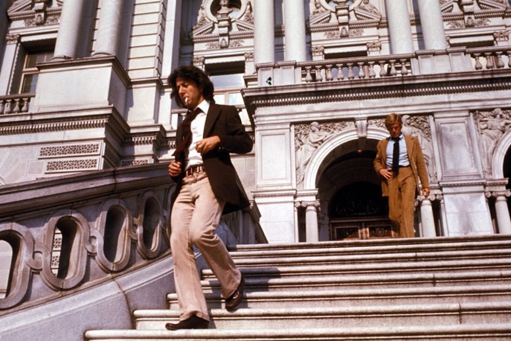 Robert Redford as Bob Woodward and Dustin Hoffman as Carl Bernstein descend the stairs in front of an ornate building in All the President's Men