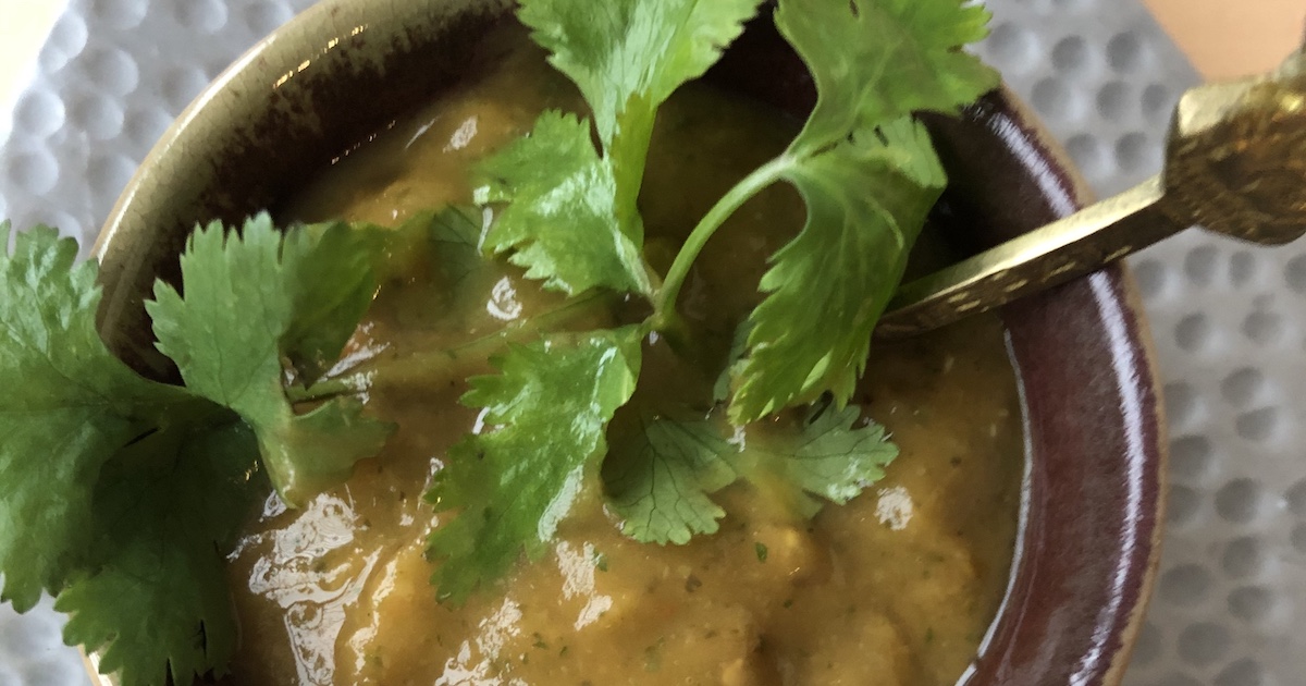 A small bowl of chutney garnished with cilantro sits on a plate