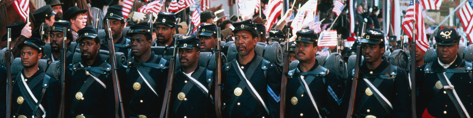 Black soldiers march in uniform in front of American flags in Glory