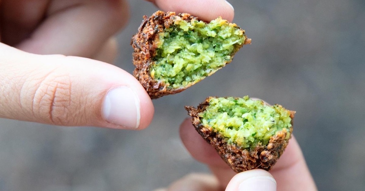 fried falafel ball torn in half showing bright green interior