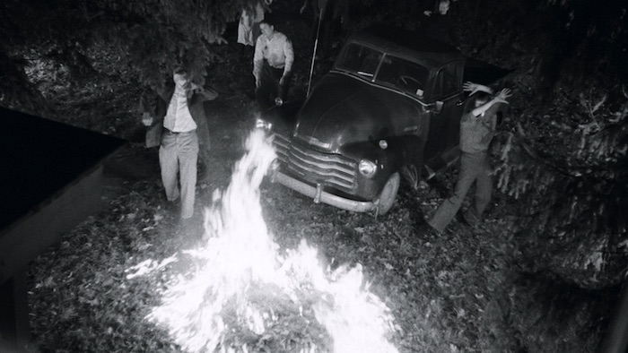 A group of zombies surround a pick-up truck and cower in fear of a fire in Night of the Living Dead (1968)