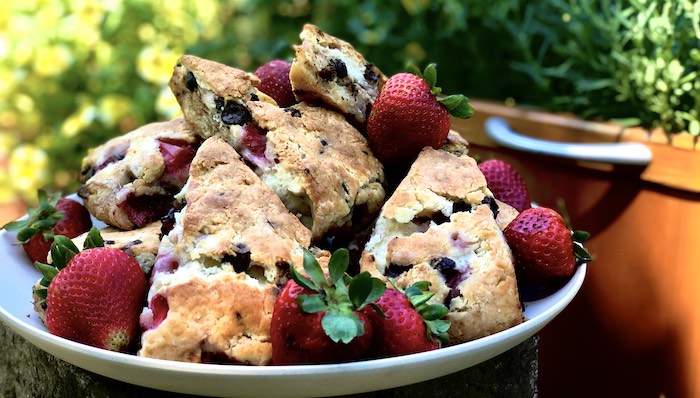 A plate of strawberry and chocolate chip scones served with fresh strawberries