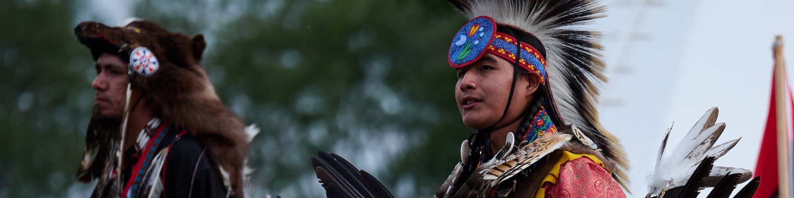 Two men wear traditional regalia