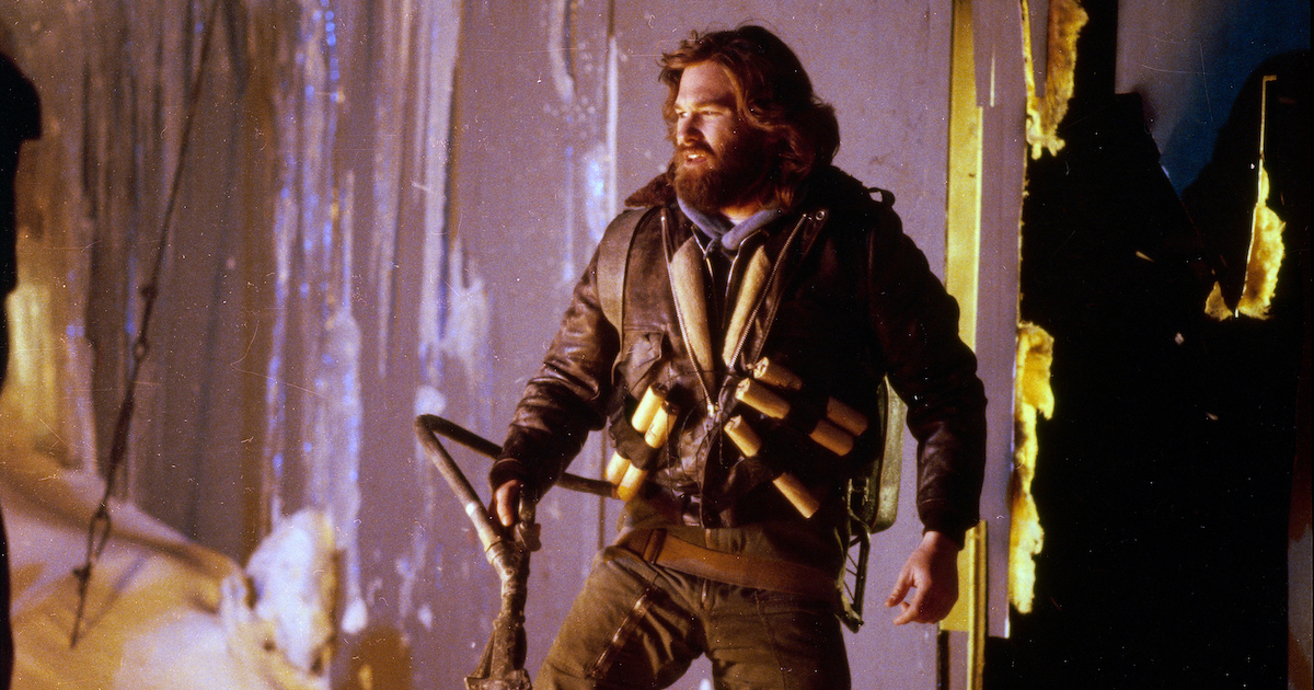 Kurt Russell wears a leather jacket with sticks of dynamite strapped to the front