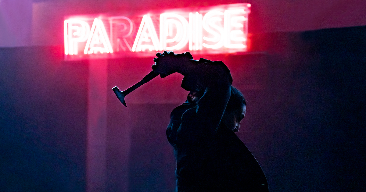Azra holds a hammer above her head in silhouette in front of a neon sign reading "paradise"