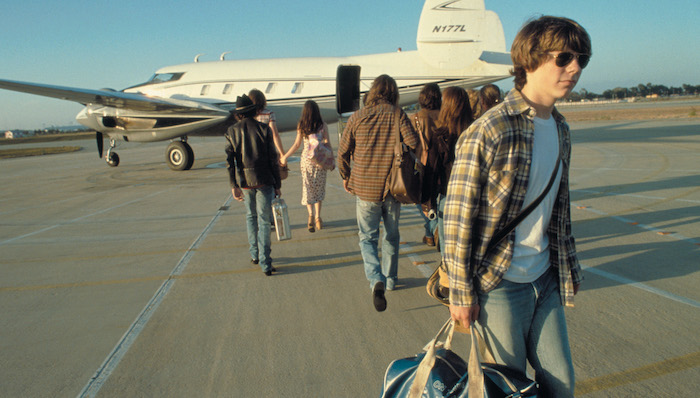 Patrick Fugit walks away from a small propeller plane while a band and it's entourage boards in Almost Famous