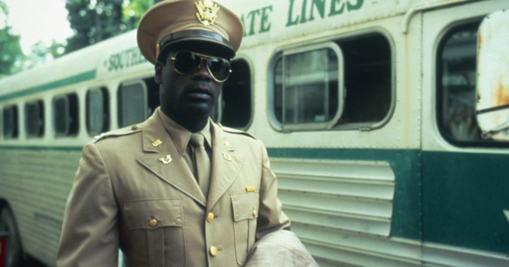 Howard E Rollins Jr wearing a US army uniform, stands next to a bus in A Soldier's Story