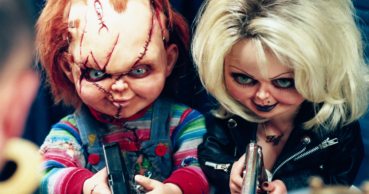 Two creepy dolls hold guns in Bride of Chucky