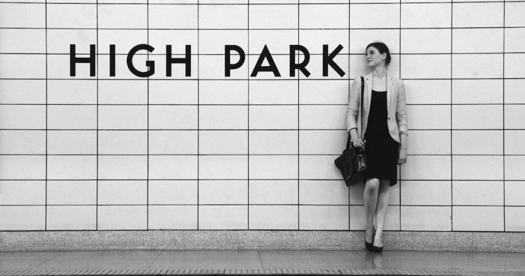 A woman stands on a subway platform next to a sign reading "High Park"