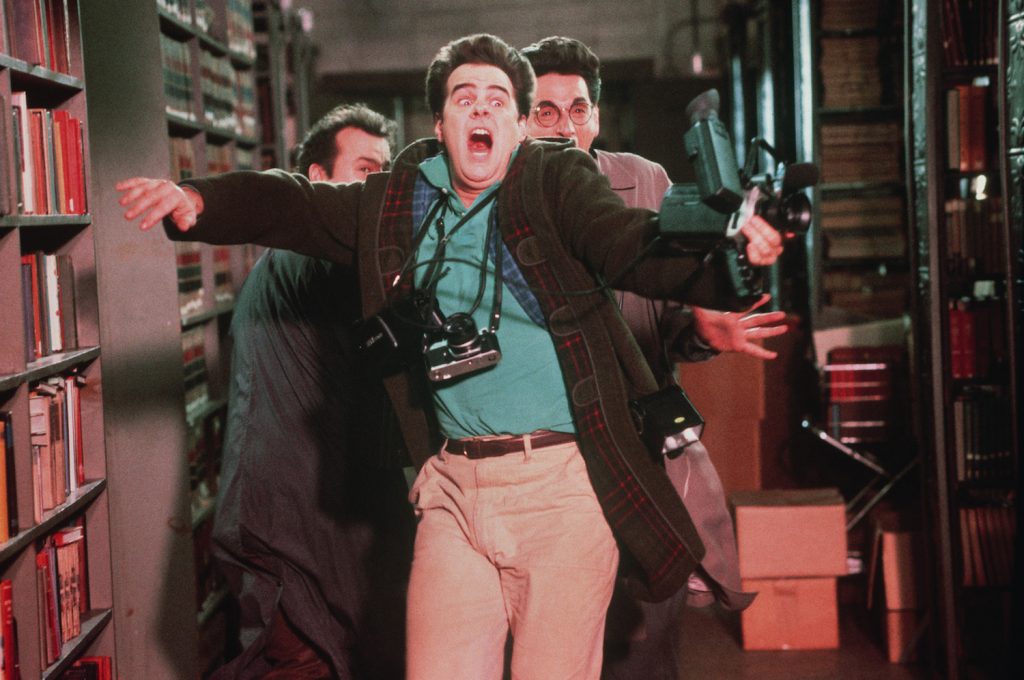 Bill Murray, Dan Aykroyd and Ivan Reitman in civilian clothing run in terror from a ghost in Ghostbusters