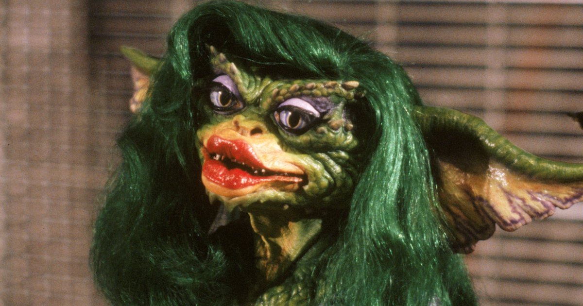 Greta Gremlin in Gremlins 2 The New Batch. A green monster with exaggerated lipstick red lips, feathered eye makeup and a mane of green hair