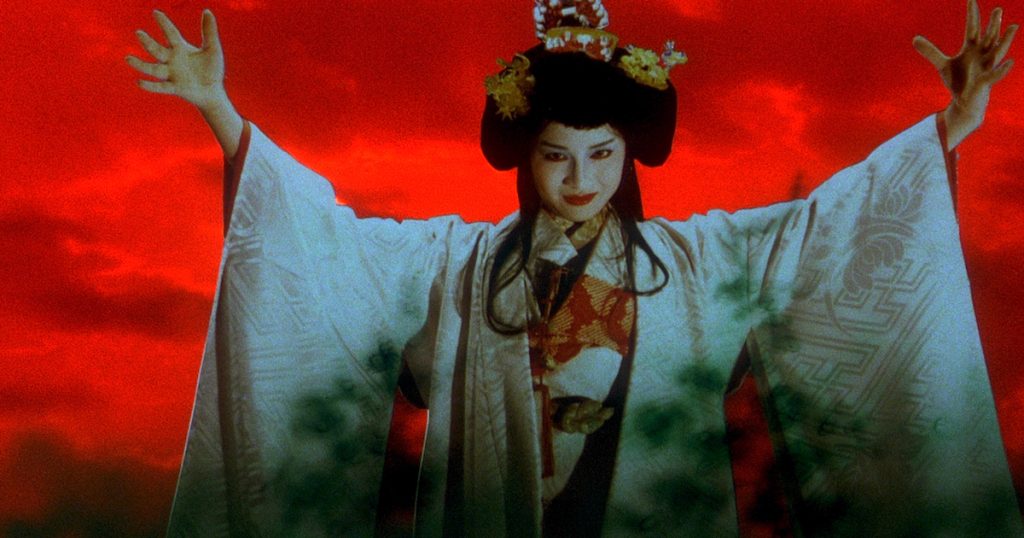 A sinister looking young woman in traditional japanese clothing holds up her arms in front of a blood red sky