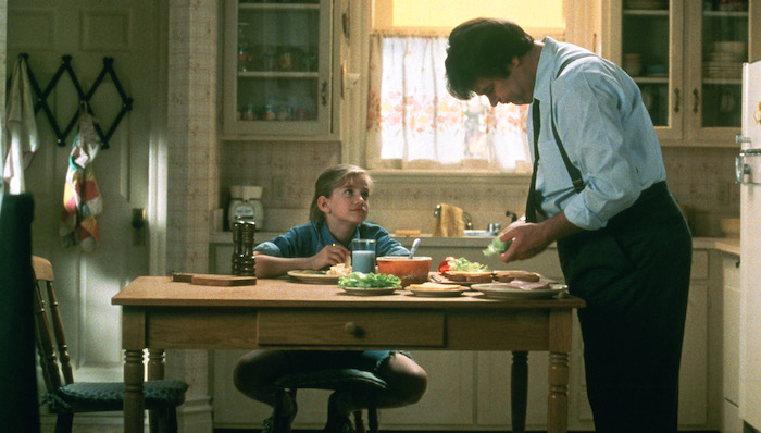 Vada (Anna Chlumsky) sits at the kitchen table as her father (Dan Aykroyd) prepares sandwiches in My Girl (1991)