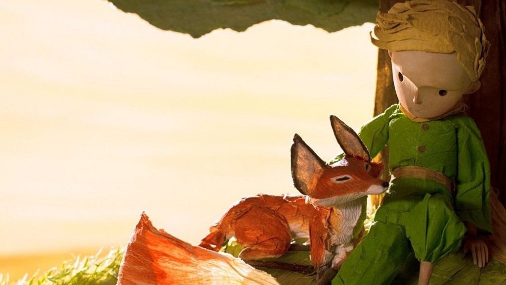 An animated boy and fox sit under a tree in The Little Prince