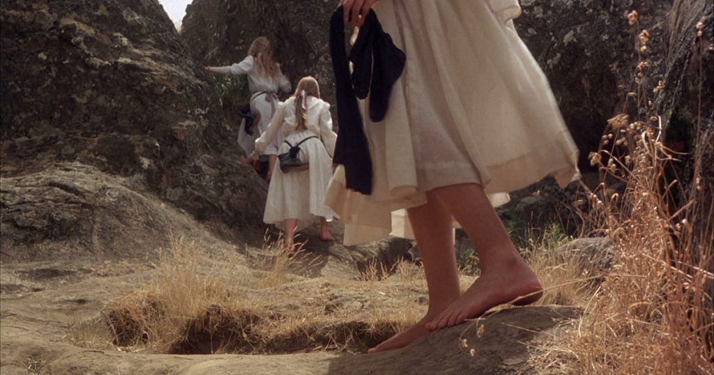barefoot girls in white dresses climb rocks 