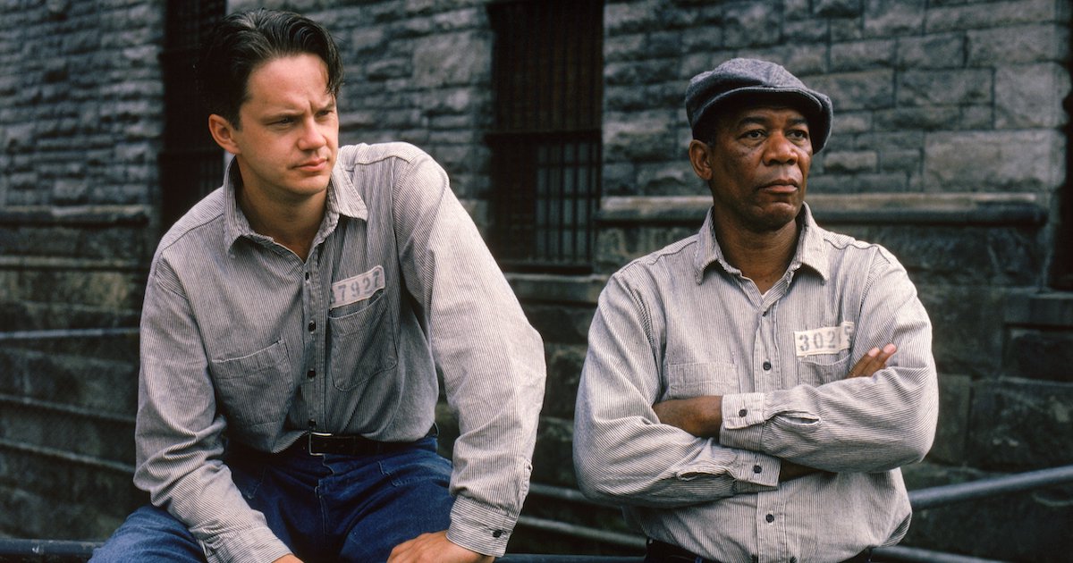 Andy (Tim Robbins) and Ellis (Morgan Freeman) lean against a railing in the prison yard in The Shawshank Redemption