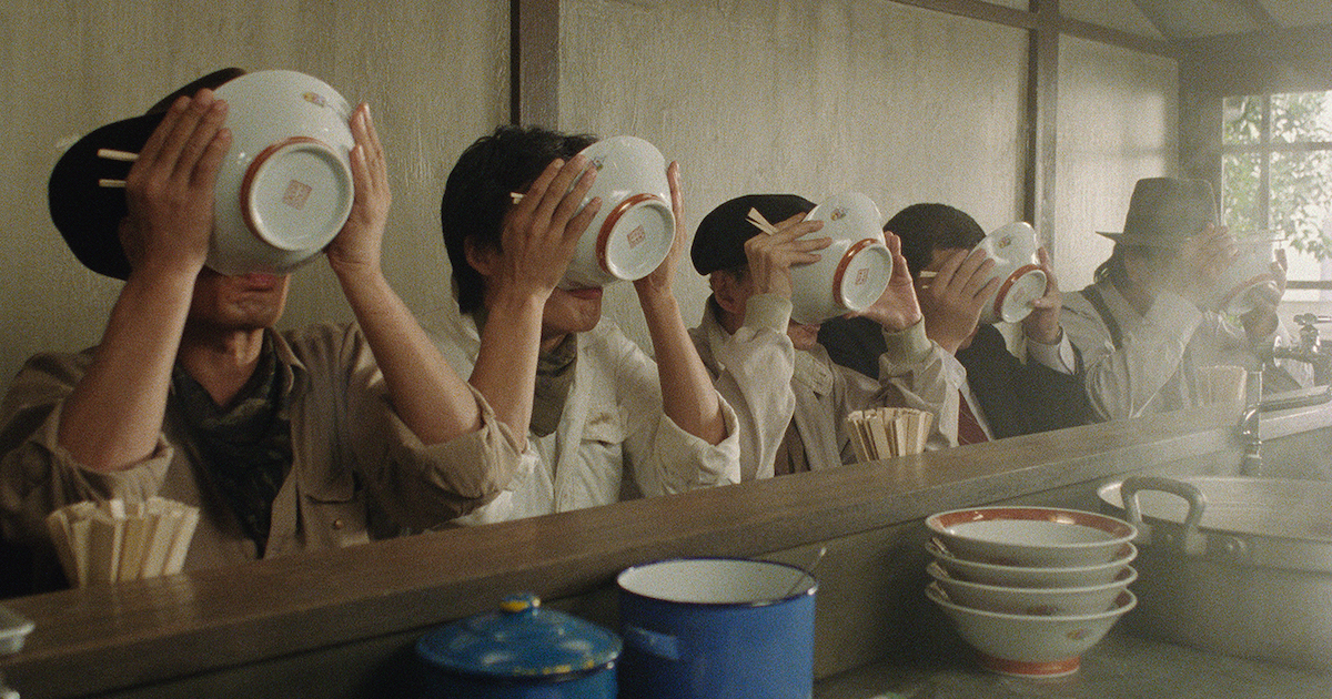 A line of customers at a counter all hold ramen bowls in front of their faces to drink the broth in Tampopo