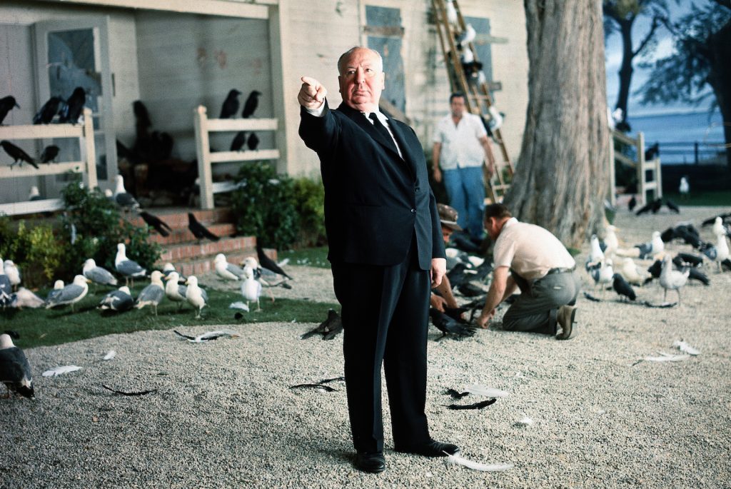 Alfred Hitchcock poses for a photo on the set of the birds